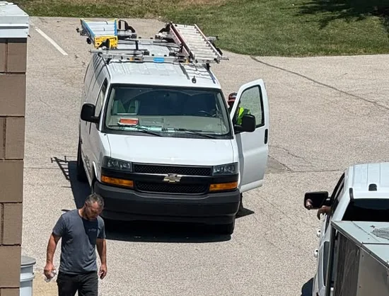 Raber service van with a roof ladder rack parked outside a municipal building during a commercial cooling service call