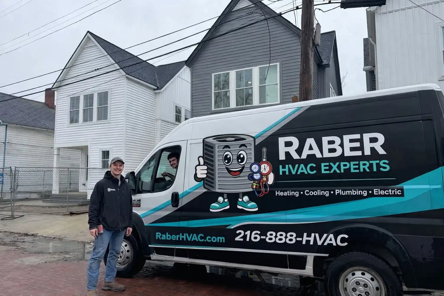 Two Raber HVAC technicians with the branded service van outside a home on a job, photographed on a Raber job in Northeast Ohio