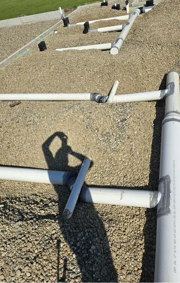 Waste and vent line layout running across a foundation pad on a new construction site